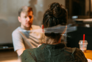 Image of two people talking through a window