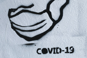 Black spray paint of Covid-19 on a white wall