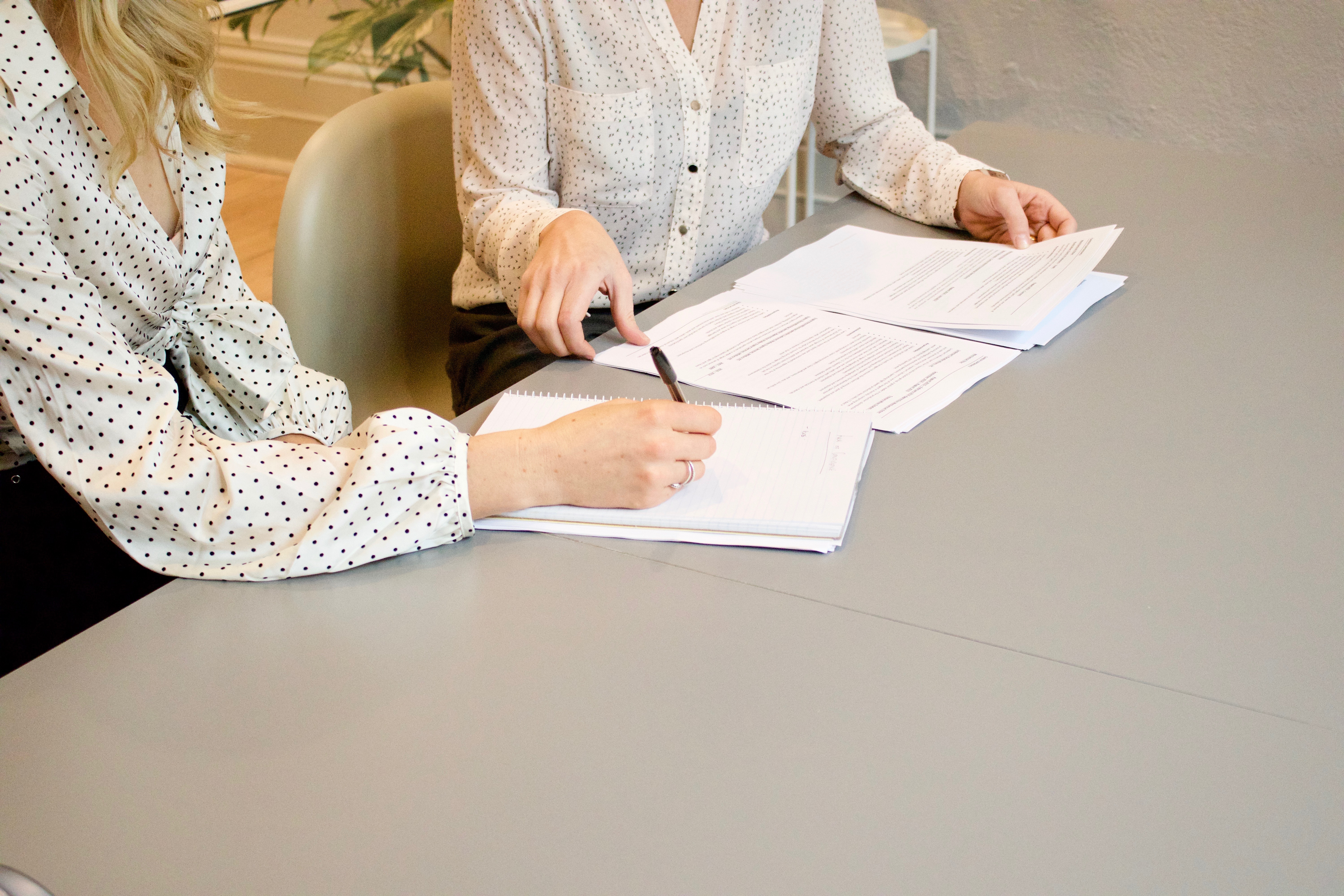 Two women writing or signing a document